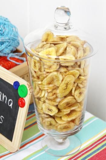 there is a bowl full of bananas next to a chalkboard with the word banana chips written on it