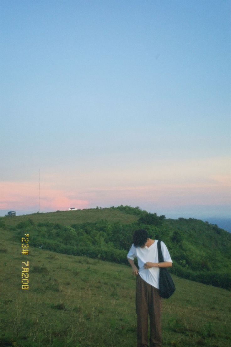 a man standing on top of a lush green hillside