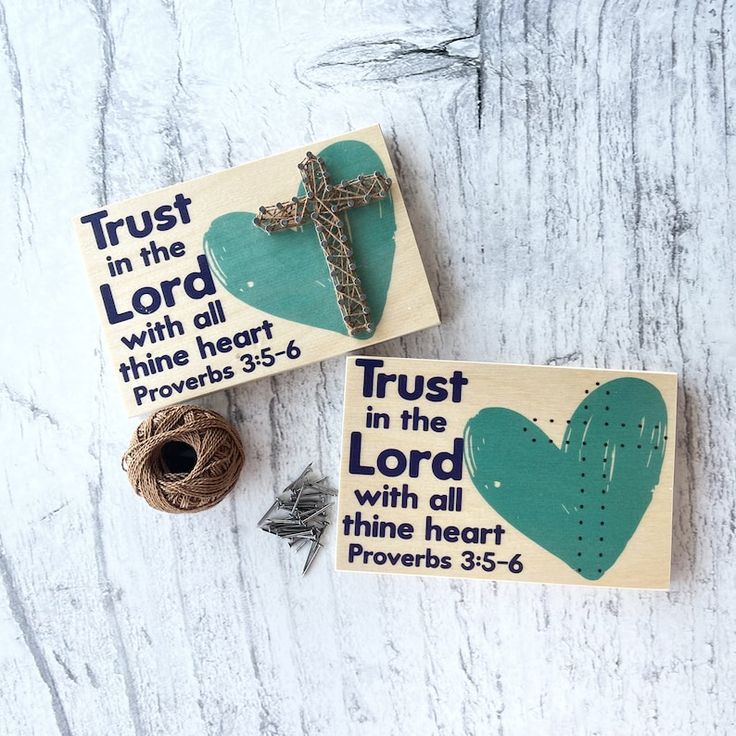 two wooden signs with words and a cross on them next to twine spools