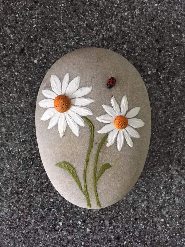 a painted rock with two daisies on it