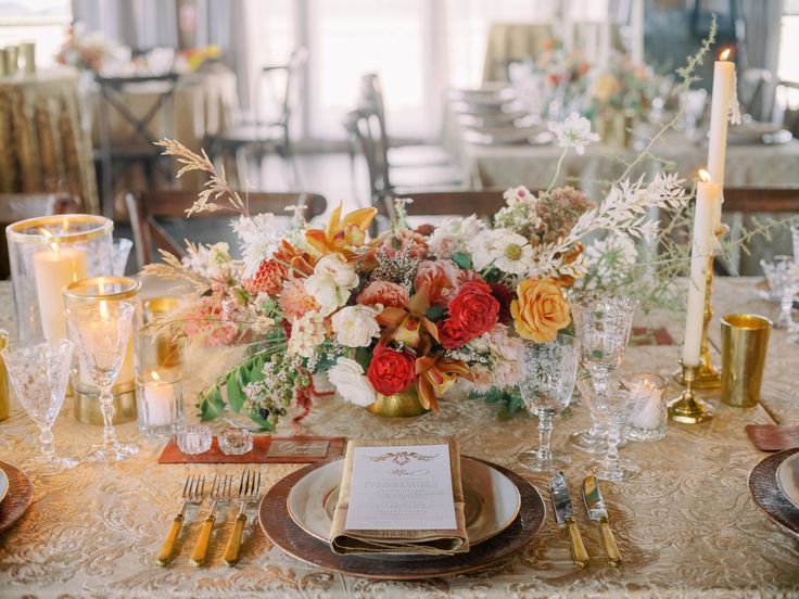 the table is set with flowers, candles and place settings for an elegant dinner party