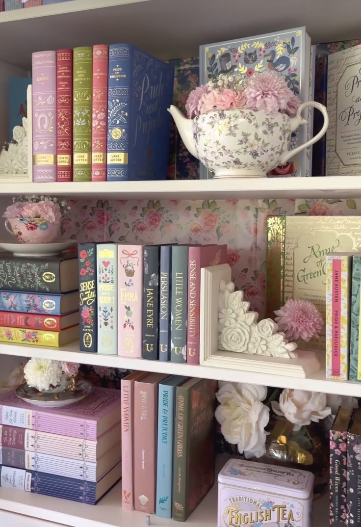 the books are lined up on the shelves in the room, and there is a teapot with pink flowers