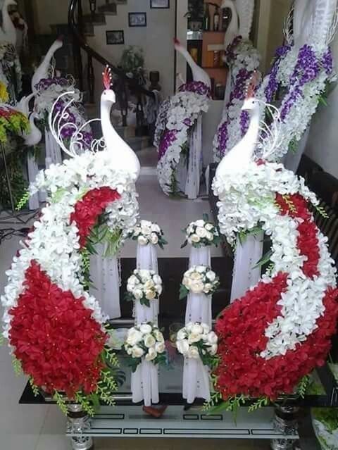 two white peacocks sitting on top of red and white flowers in front of a mirror