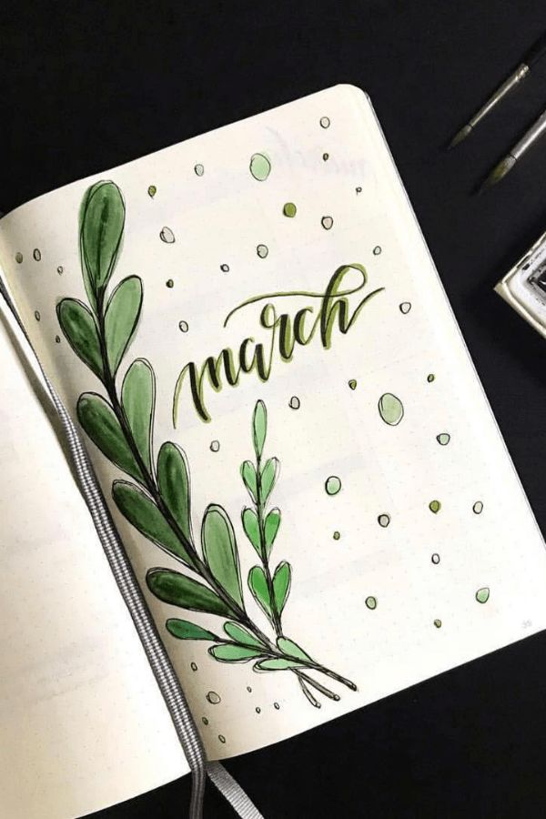 an open notebook with the word march written in cursive writing and green leaves