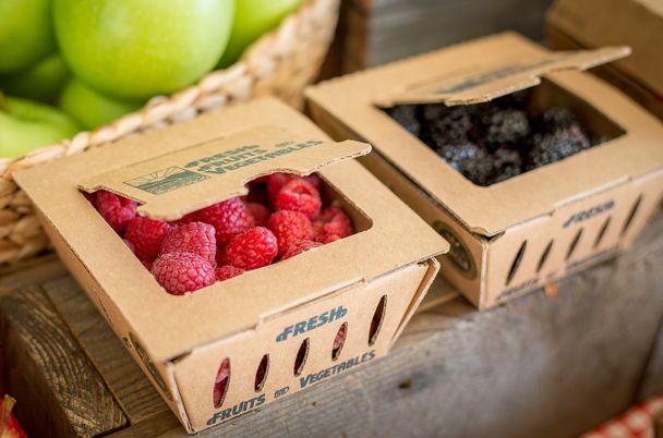 two boxes filled with raspberries sitting on top of a table next to green apples