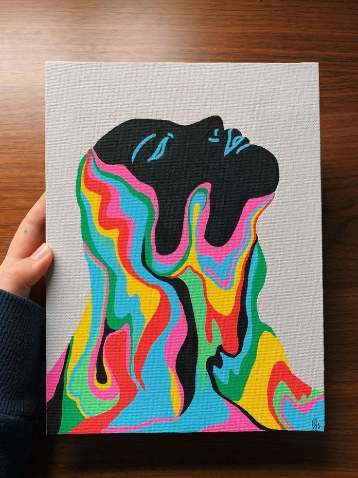 a person is holding up a colorful dog art piece on a wooden table with their hand