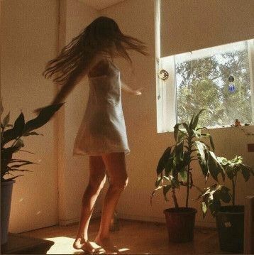 a woman standing in front of a window with her hair flying through the air,