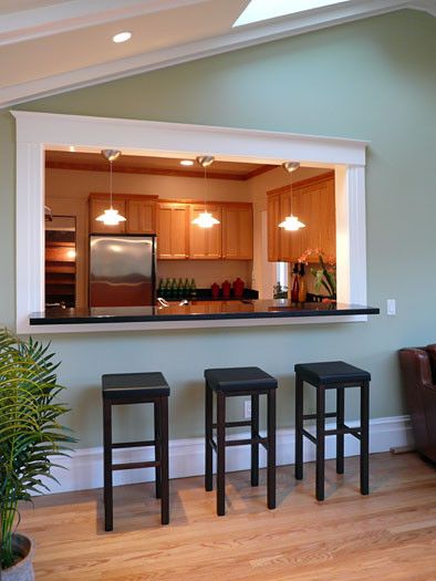 three stools sit in front of a bar with an open window to the kitchen