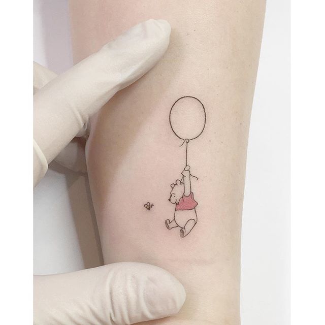 a person with a small tattoo on their arm holding a balloon and flying it in the air