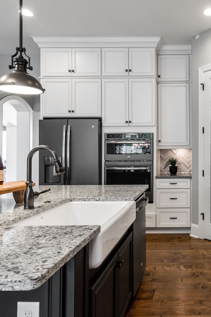 a kitchen with white cabinets and granite counter tops, black appliances and wood flooring