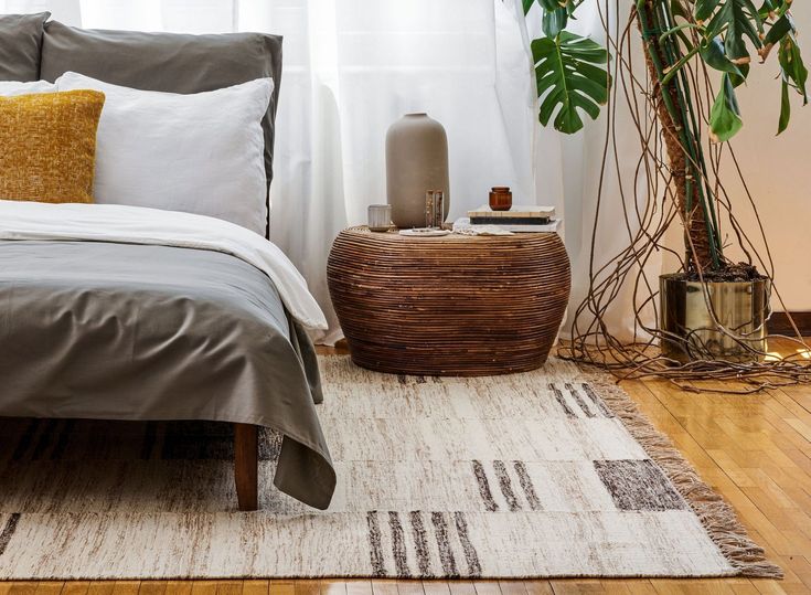 a bed sitting on top of a wooden floor next to a plant in a bedroom