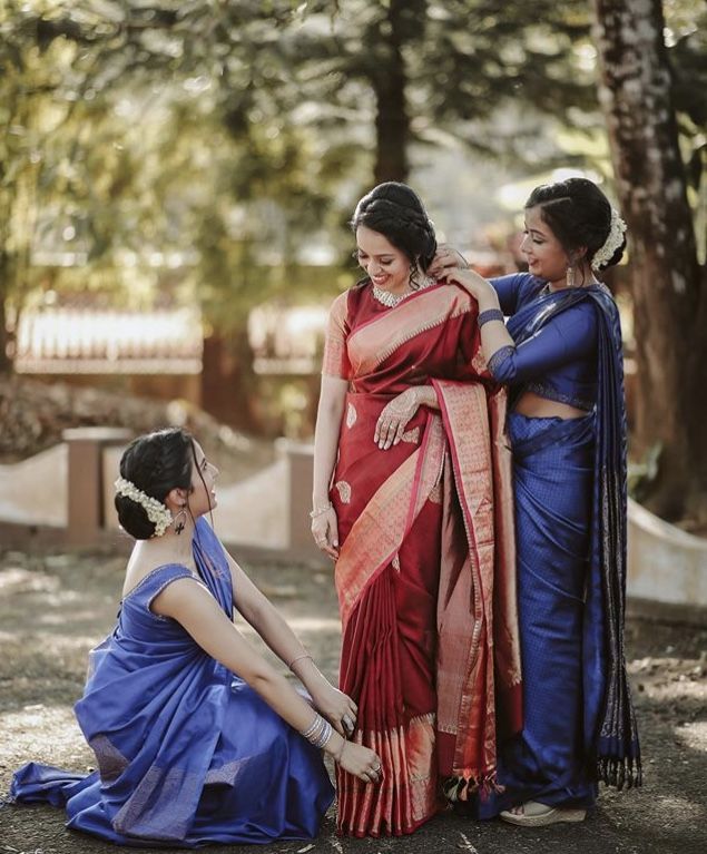 three women in blue and red sari standing next to each other on the ground