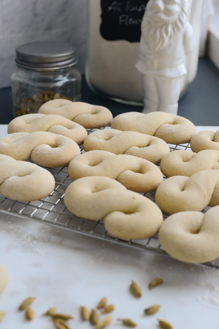 several doughnuts are cooling on a rack in front of a jar of pistachio seeds