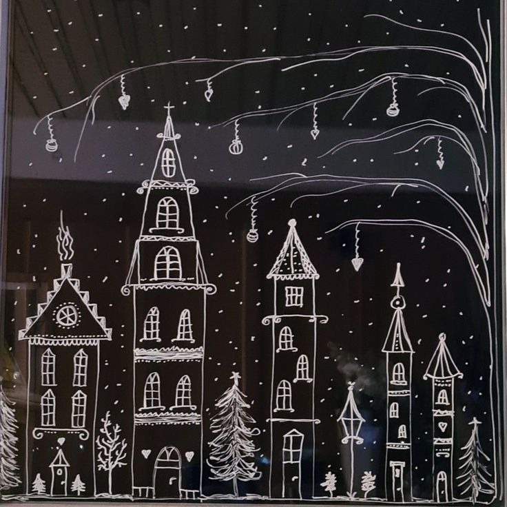 the window is decorated with white frosting and hand drawn christmas trees, houses, and snowflakes