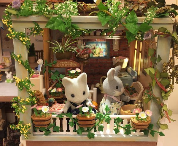 two stuffed animals sitting on top of a table next to flowers and potted plants