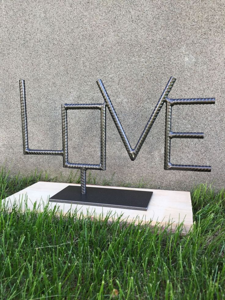 a metal sculpture with the word love spelled in cursive letters on top of it