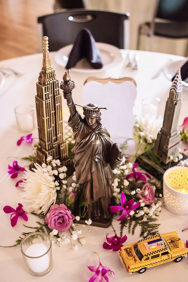 a table topped with flowers and statue of liberty on top of a white table cloth