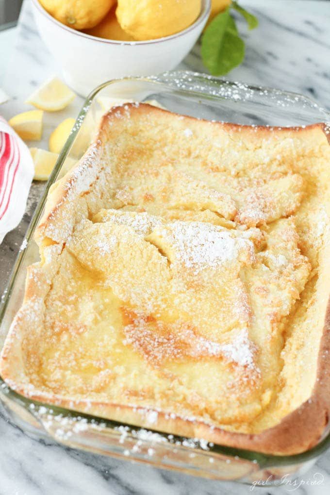 a casserole dish with powdered sugar on top, sitting on a marble counter