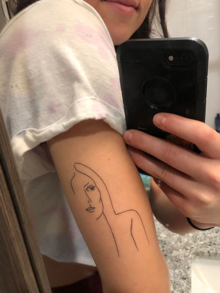 a woman with a tattoo on her arm taking a selfie