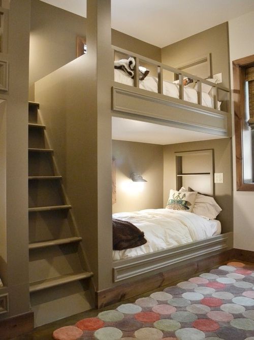 a bedroom with bunk beds and stairs leading up to the top floor, along with a rug on the floor