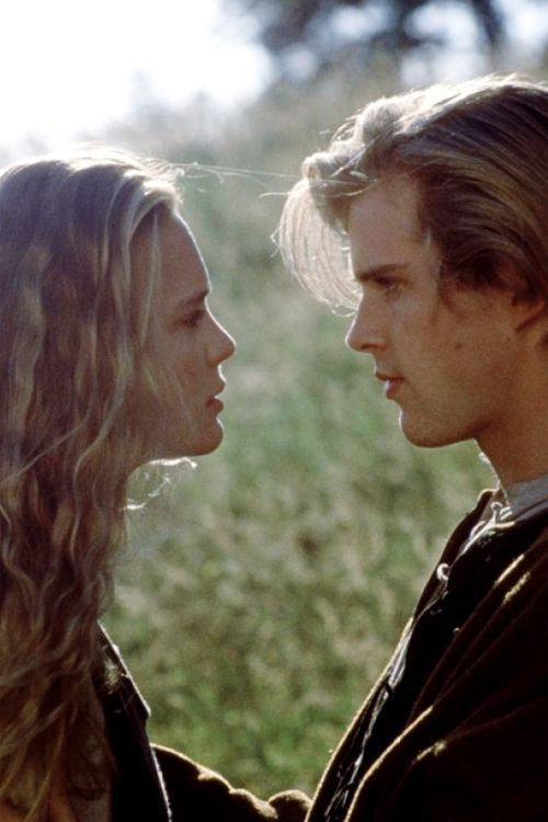 a man and woman standing next to each other in front of a green grass covered field