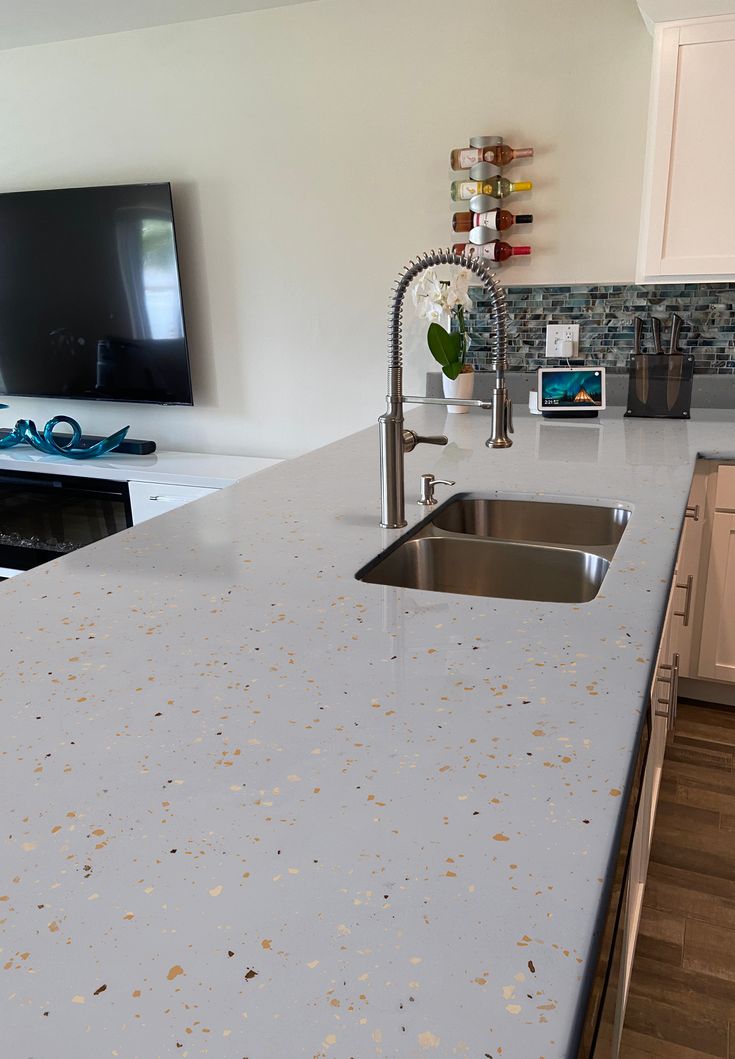 a kitchen counter with a sink and a television on the wall in front of it