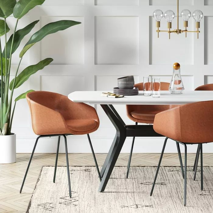 a dining room table with chairs and a potted plant in the corner next to it