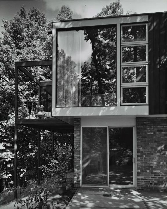 a black and white photo of a house in the woods