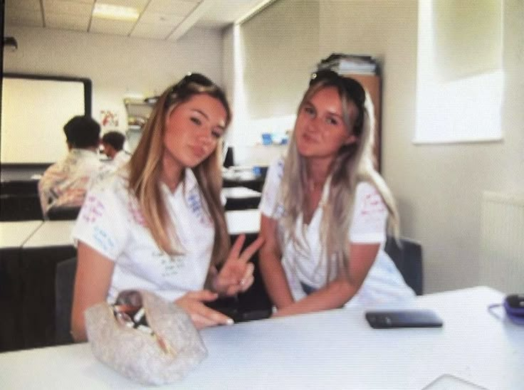 two women sitting at a table in an office