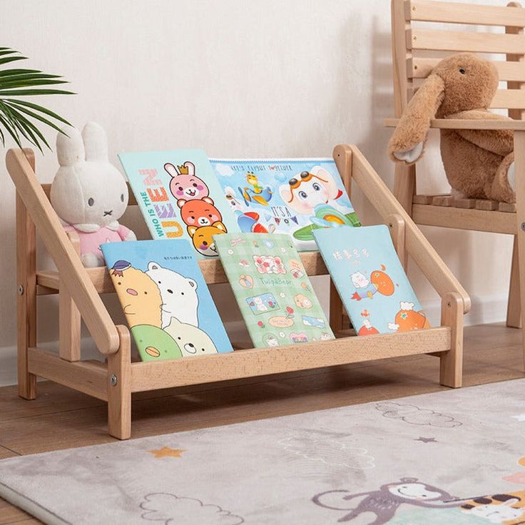 children's books are placed in a wooden holder on the floor next to a teddy bear