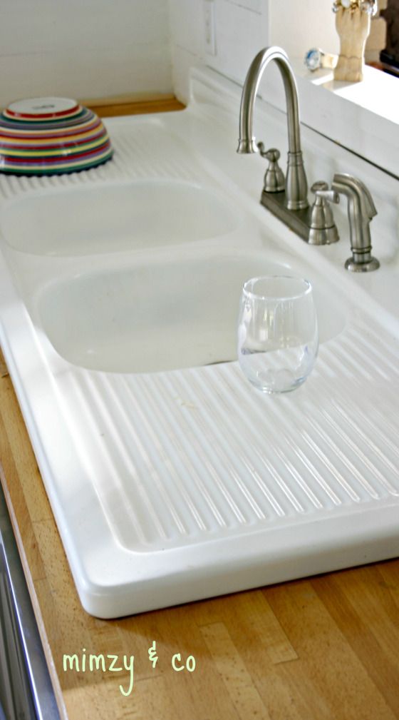 a kitchen sink with a glass on the counter top next to a faucet