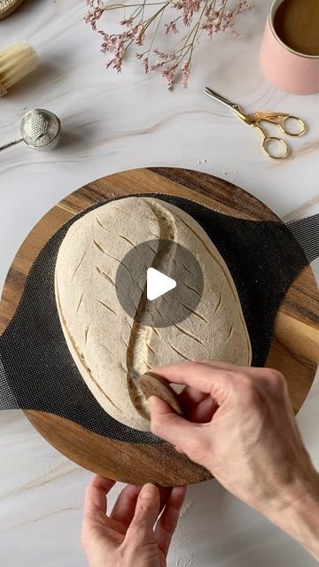 a person is making some bread on a wooden board with scissors and other items around the table