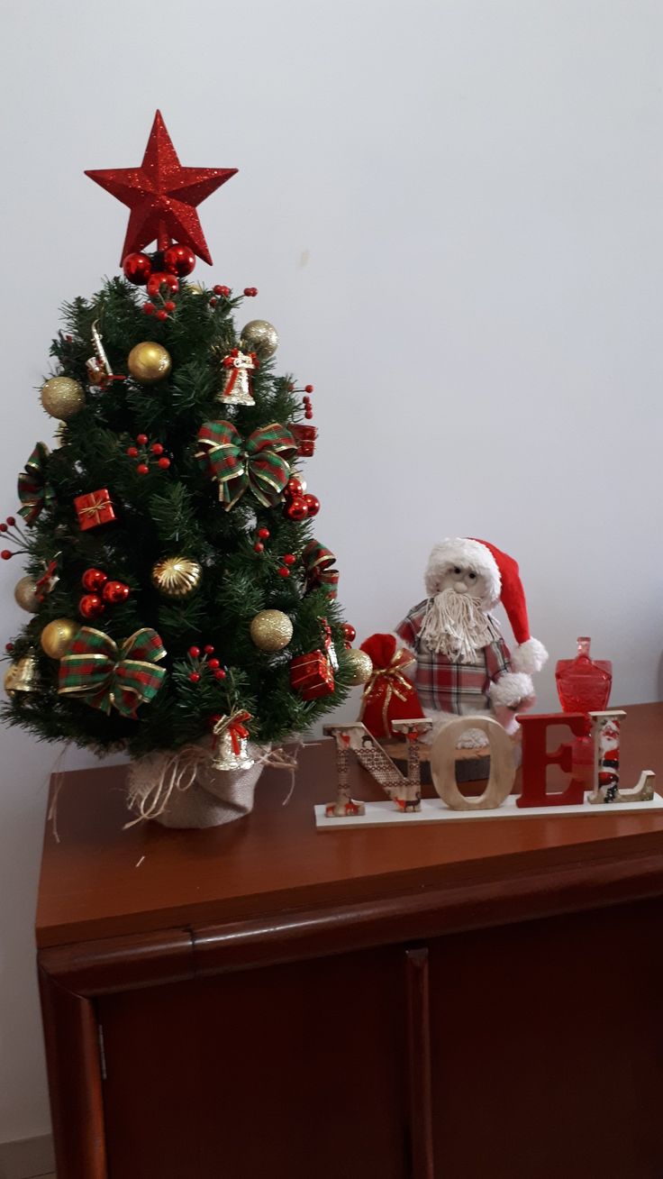 a small christmas tree sitting on top of a wooden table next to a santa clause