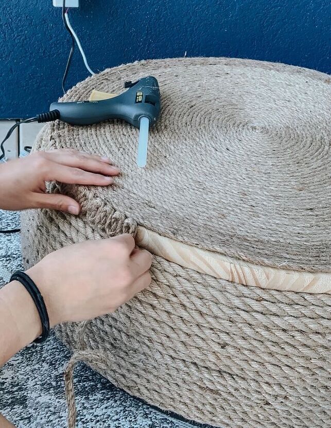 a person is working on a large round ottoman that has been made out of jute