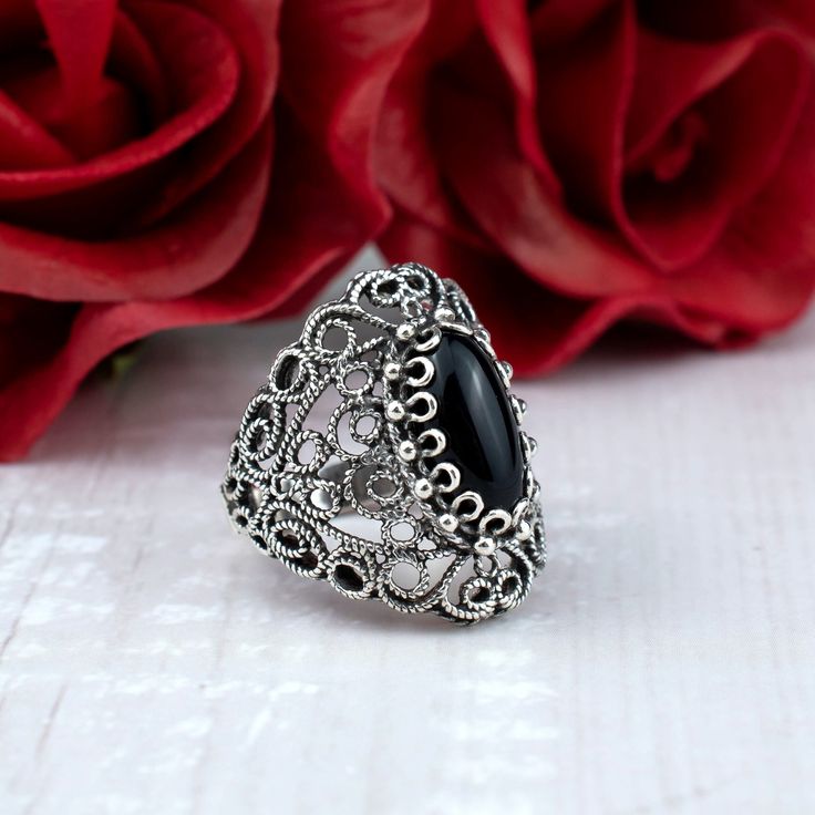 This stunning cocktail ring features an intricate filigree lace design and a 7x14 mm black onyx gemstone. Black onyx is a stone of protection and grounding, making it the perfect choice for a statement cocktail ring. It is said to absorb negative energy and promote inner strength.  Ring Face Length is 0.65 inches and Width is 0.30 inches  The ring is made from high-quality 925 sterling silver and is finished to a high shine. The lace detailing is exquisitely crafted and adds a touch of elegance to the ring. The ring comes with a silver polish cloth and a luxurious gift box, making it the perfect gift for any special occasion. This statement piece is perfect for any occasion, from a night out on the town to a special event. It is sure to turn heads wherever you go. Whether you are looking f Black Sterling Silver Filigree Ring As A Gift, Ornate Black Sterling Silver Rings, Ornate Black Filigree Jewelry, Ornate Black Rings As Gift, Ornate Black Rings For Gifts, Ornate Black Rings For Gift, Black Intricate Design Jewelry As Gift, Ornate Black Wedding Ring, Ornate Black Jewelry With Intricate Design