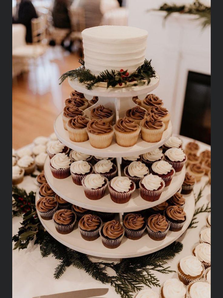 a three tiered cake and cupcakes on a table