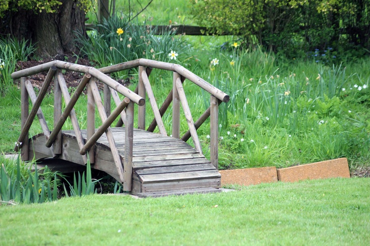 a small wooden bridge in the middle of some grass