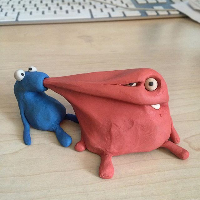 two clay figurines sitting next to each other on a wooden table with words written below them