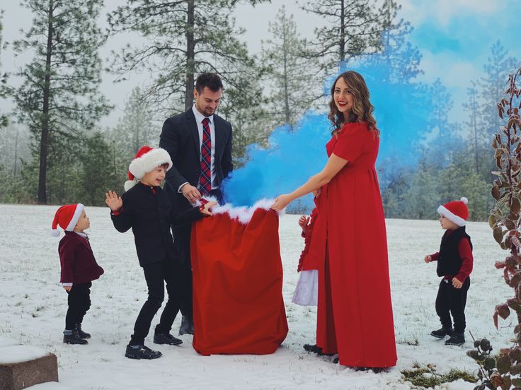 a man and two children are dressed up in santa's hats as they stand next to a red blanket