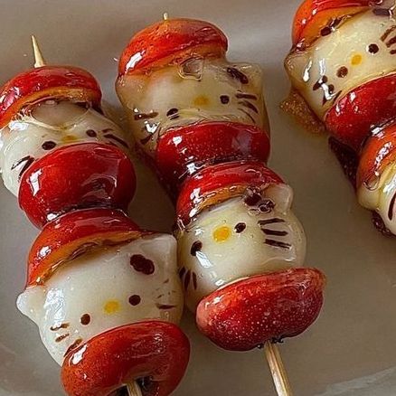 hello kitty skewers are on a plate with toothpicks wrapped in cheese