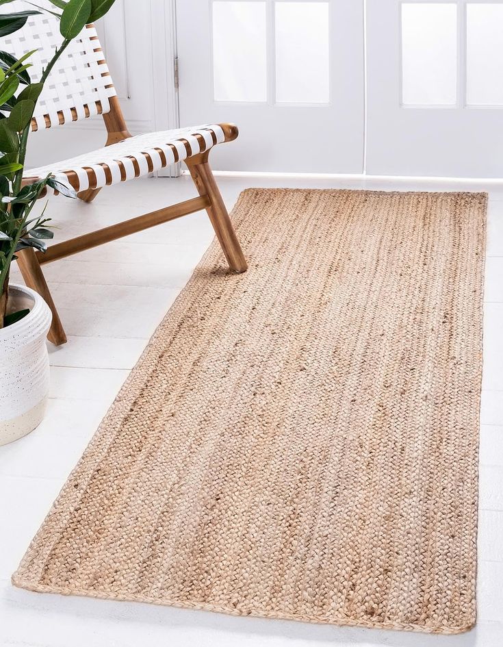 a large rug is on the floor in front of a chair and potted plant