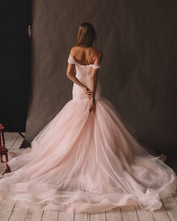 a woman in a pink dress is standing near a chair and posing for the camera