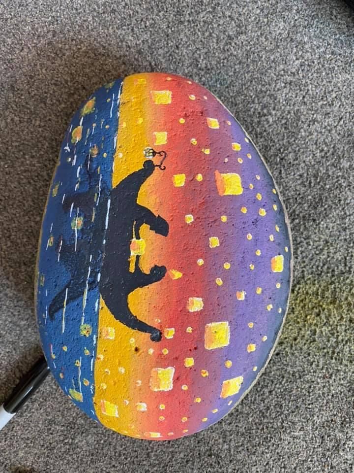 a painted rock sitting on top of a carpeted floor next to a computer mouse