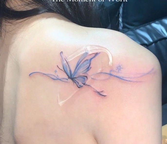 a woman's back shoulder with a butterfly tattoo on the left side of her neck