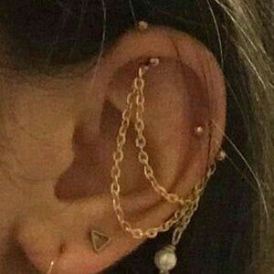 a close up of a person's ear wearing gold chain and pearled earrings