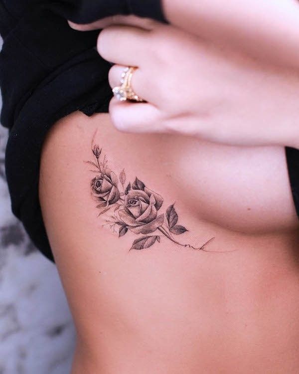 a woman with a rose tattoo on her back is looking down at her lower body