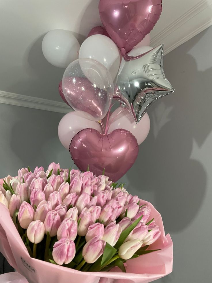 a bouquet of tulips and balloons are on display in front of a wall