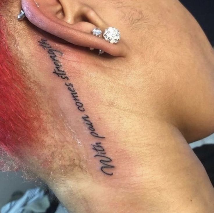 a woman with red hair has a tattoo on her lower back and behind her ear