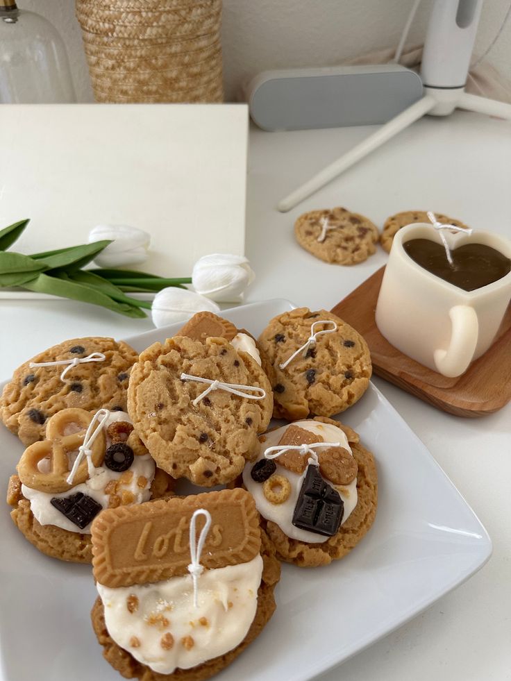 cookies with white icing and chocolate chips on a plate next to a cup of coffee