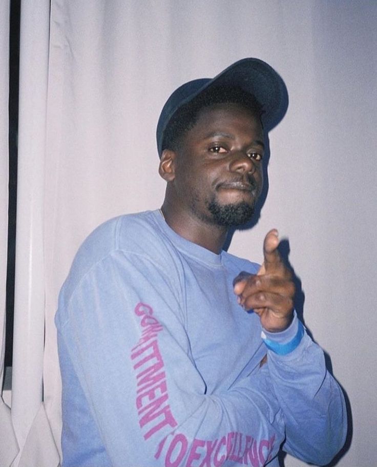 a man in a blue sweatshirt and hat pointing to the side with his finger up